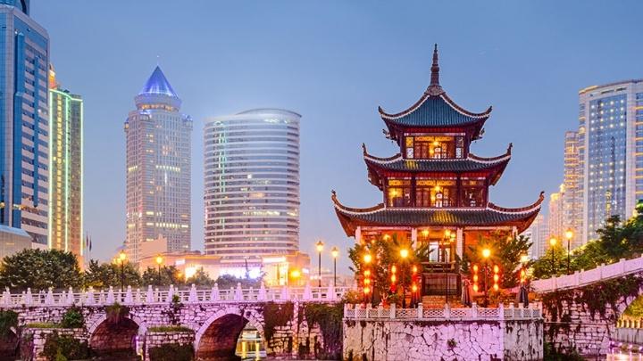 Traditional Chinese building on a river in front of modern cityscape